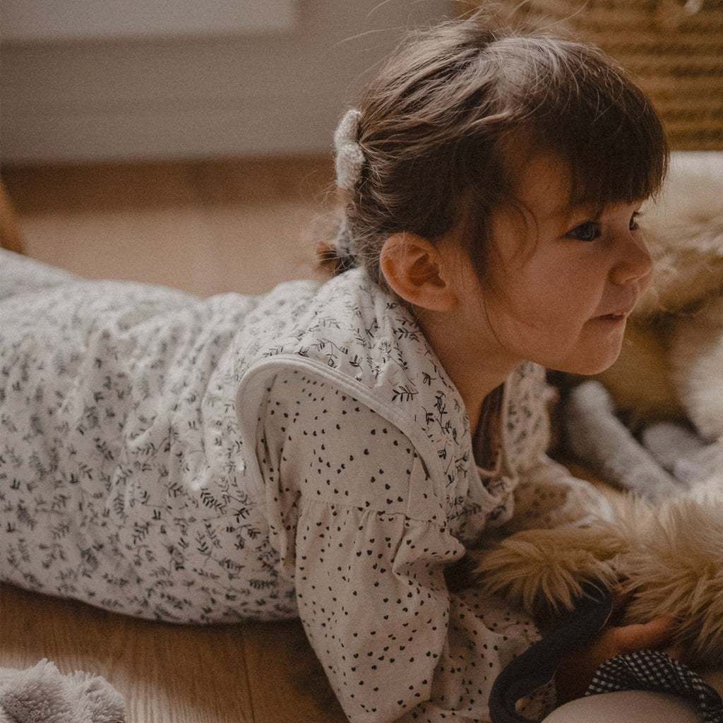 Petite fille allongée et qui joue dans sa gigoteuse de voyage Rosemary