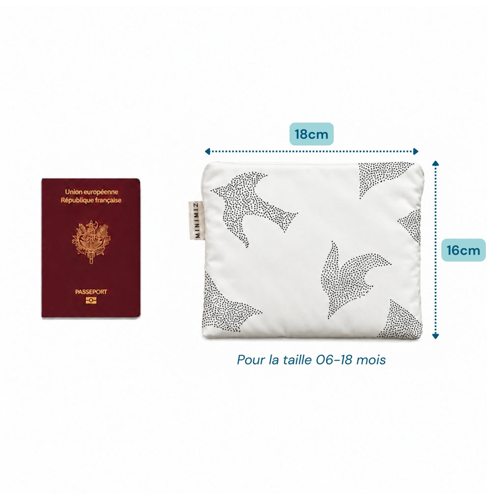 Gigoteuse Birds pliée dans son pochon de 18 x 16 cm à côté d'un passeport, idéale en avion